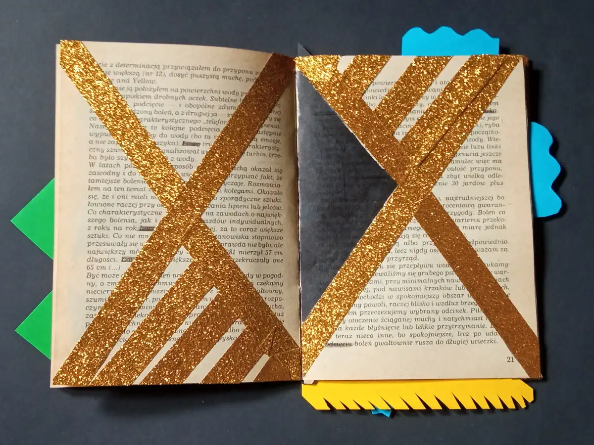 Foto de un libro abierto volteado en horizontal con recortes y papeles pegados